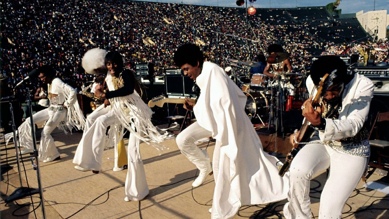 a band in white fringed outfits on stage